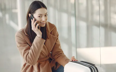 Traveller with a suitcase talking on the phone at an airport